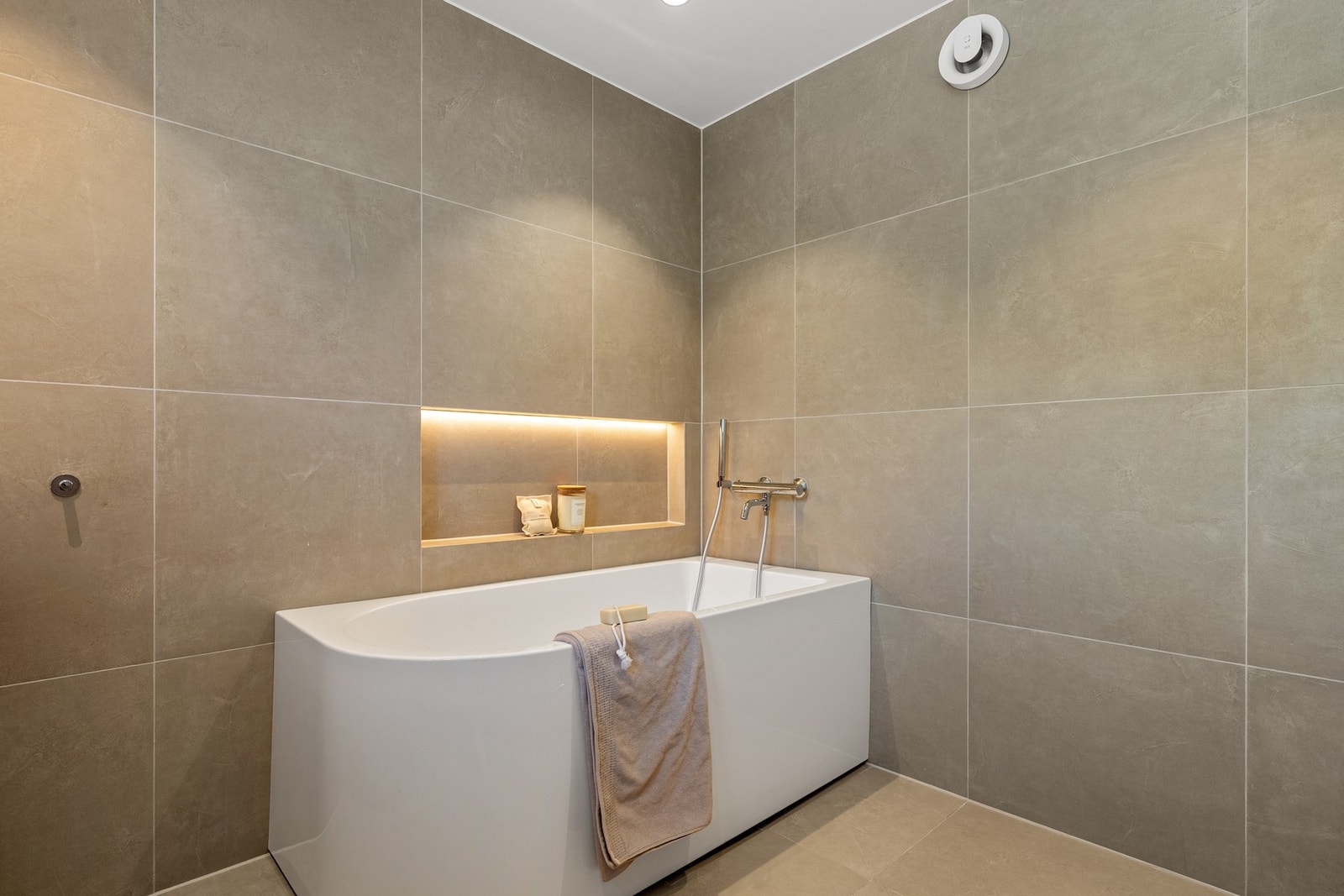 Badet på 5,6 kvm er innredet med baderomsinnredning, speil med lys og vegghengt toalett. Det praktiske badekaret med nisje i veggen gir rommet en deilig spafølelse. Galleribilde