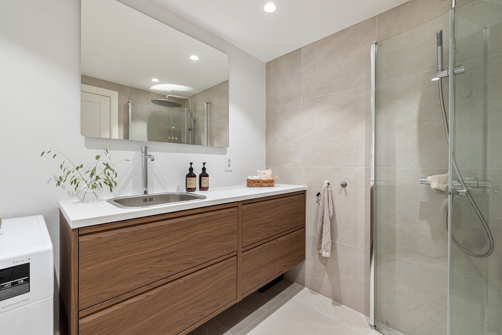 Badet i underetasjen på 4,5 m² er stilrent og funksjonelt, med en flott kombinasjon av fliser og slette malte overflater på veggene som gir en lys og innbydende atmosfære. Galleribilde