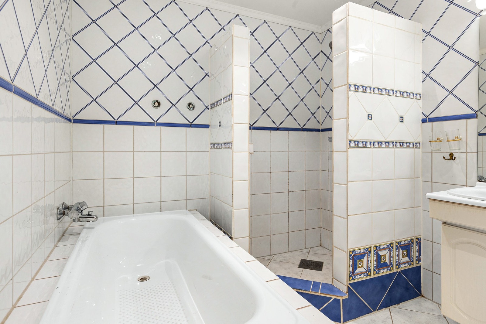 Rommet er utstyrt med gulvstående toalett, innredning med to servanter, innebygget badekar og dusjnisje med oppkant ut til rommet Galleribilde