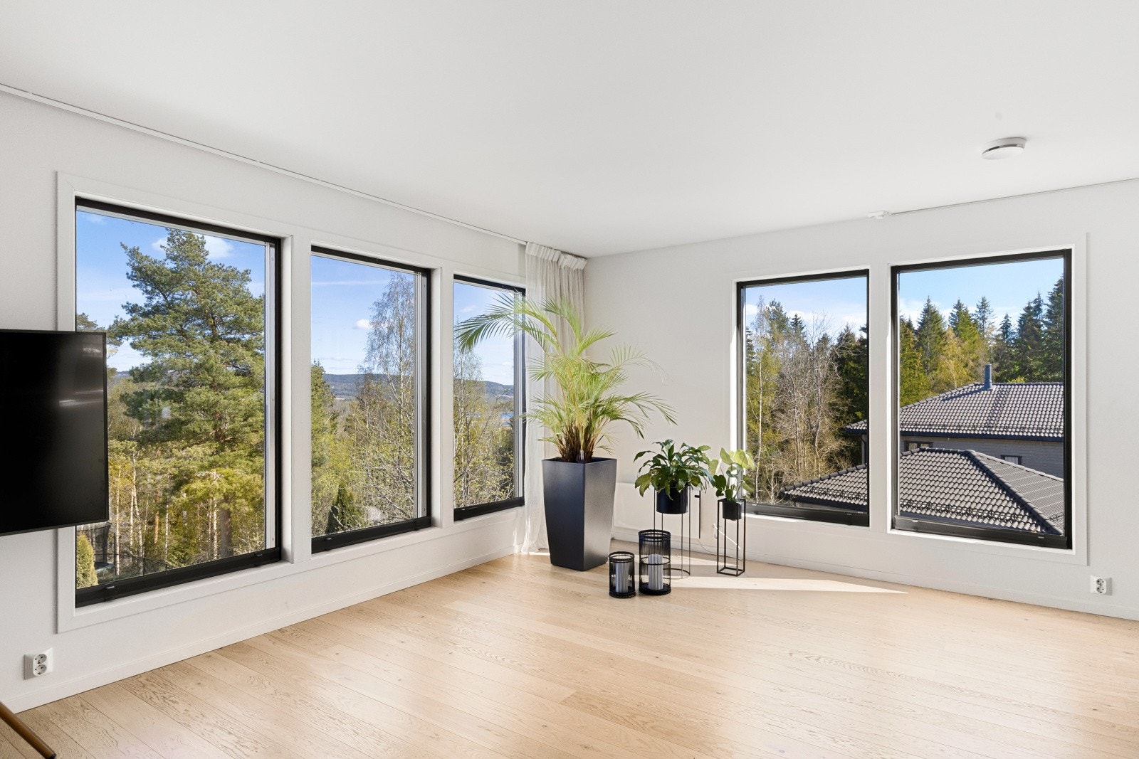 Et herlig allrom hvor store vinduer sender dagslyset inn fra flere retninger - samtidig som omgivelsene blir trukket visuelt inn i rommet. Galleribilde