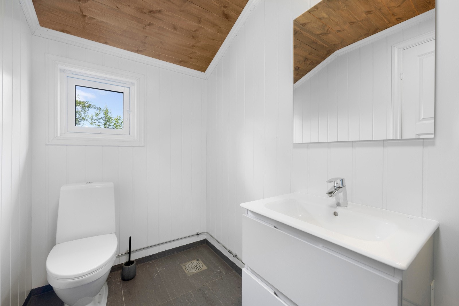 Flis på gulv og mdf-plater på vegg, panel i himling. Rommet er innredet med servantskap og toalett samt opplegg for vaskemaskin. Galleribilde