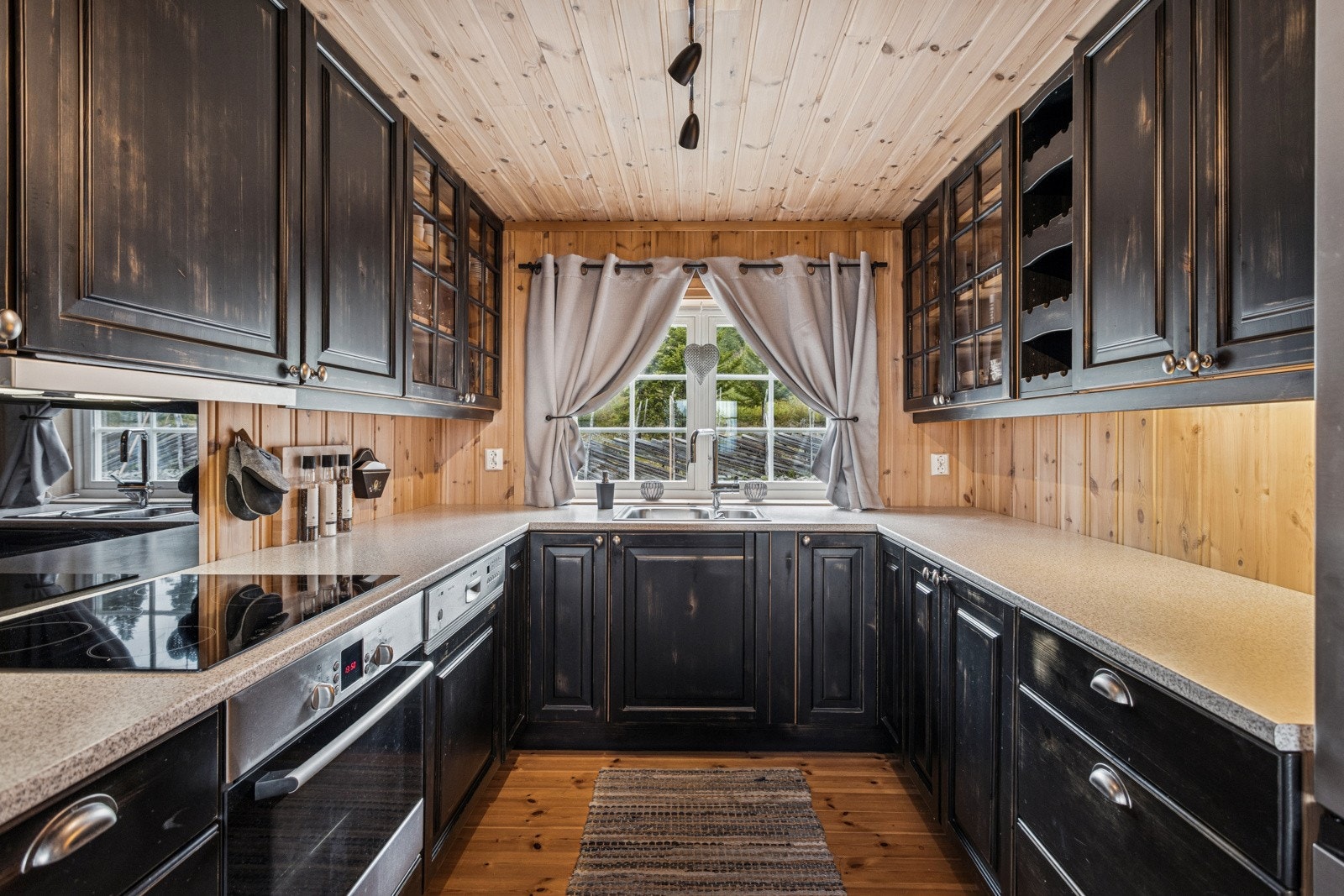 Benkeplater i laminat med god plass til matlaging og baking. Innredningen har integrerte løsninger for komfyr, koketopp og oppvaskmaskin. Ventilator over koketopp. Galleribilde