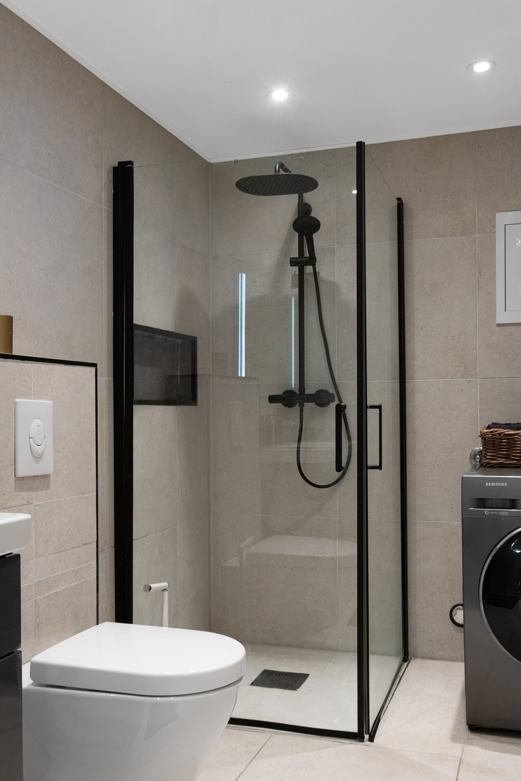 Det er flislagt og har elektriske varmekabler. Innredningen består av servant med underskap, vegghengt toalett, dusjhjørne og speil med belysning. Galleribilde