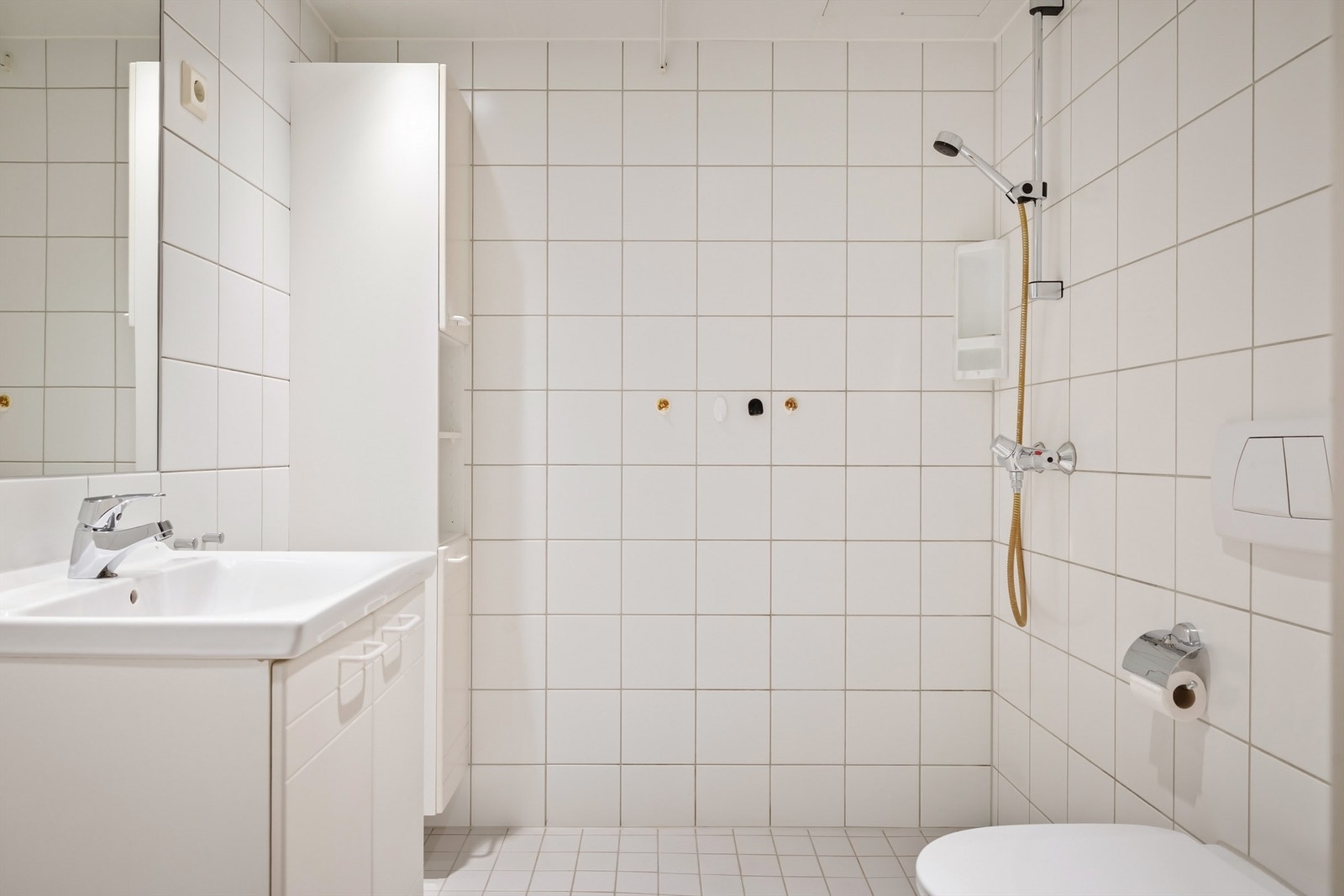 Baderomsinnredning med vegghengt servantskap med speil over, samt dusjhjørnet og vegghengt toalett Galleribilde