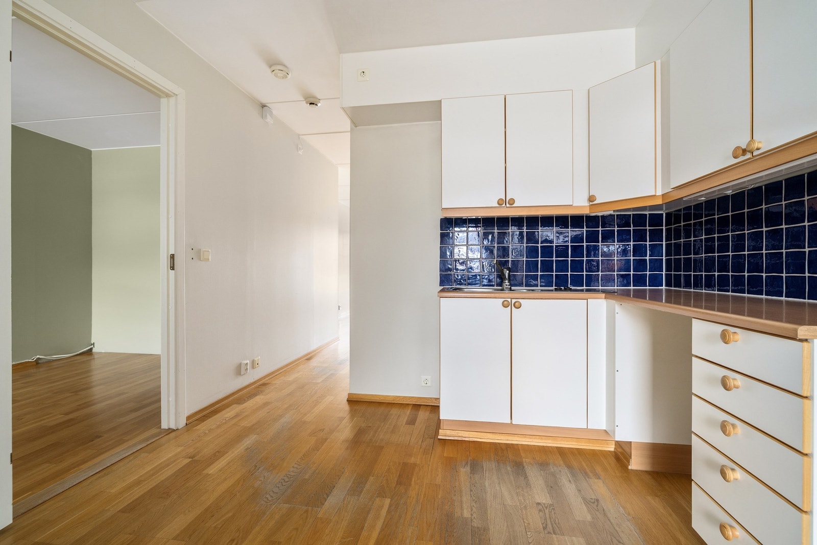 Kjøkkeninnredning med glatte fronter, benkeplate av laminat og dobbel oppvaskkum av rustfritt stål med ett-greps armatur, samt opplegg for oppvaskmaskin Galleribilde