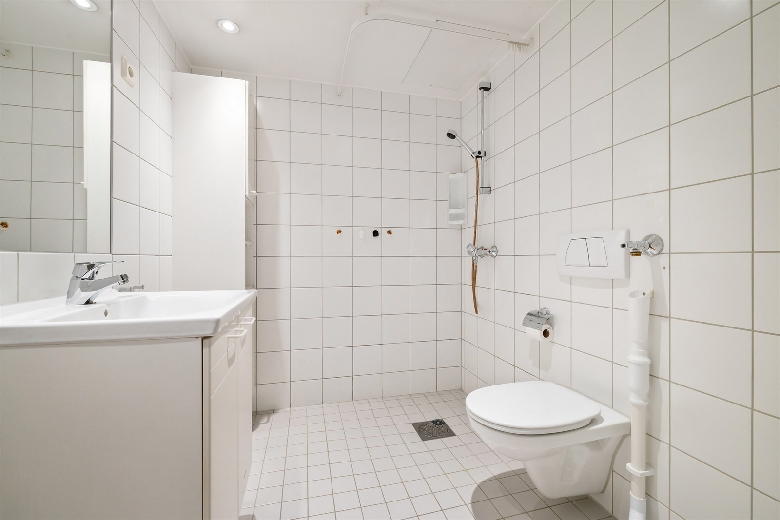 Flislagt baderom med gulvvarme, downlights og opplegg for vaskemaskin Galleribilde