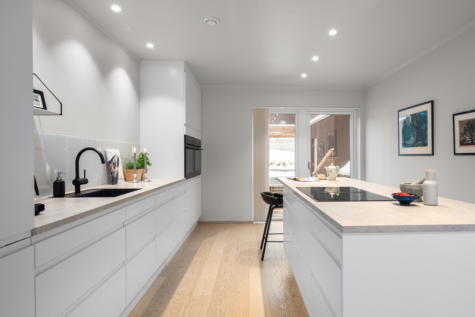 Kjøkkenet ligger i en åpen og sosial løsning mot spisestuen. Innredningen har lyse, slette fronter kombinert med god skap- og benkeplass. Benkeplaten i laminat har underlimt kum i kompositt og gir rikelig med arbeidsflate. Galleribilde