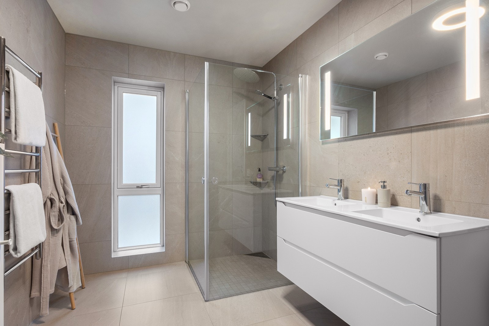 Boligen har to bad, begge fra byggeår 2021 og plassert vegg i vegg med lik utførelse og materialvalg. Dusjhjørnet er adskilt med glassvegger og har mosaikkfliser på gulv, takdusj og hånddusj. Det er også praktiske nisjer for oppbevaring av såpeprodukter. Galleribilde