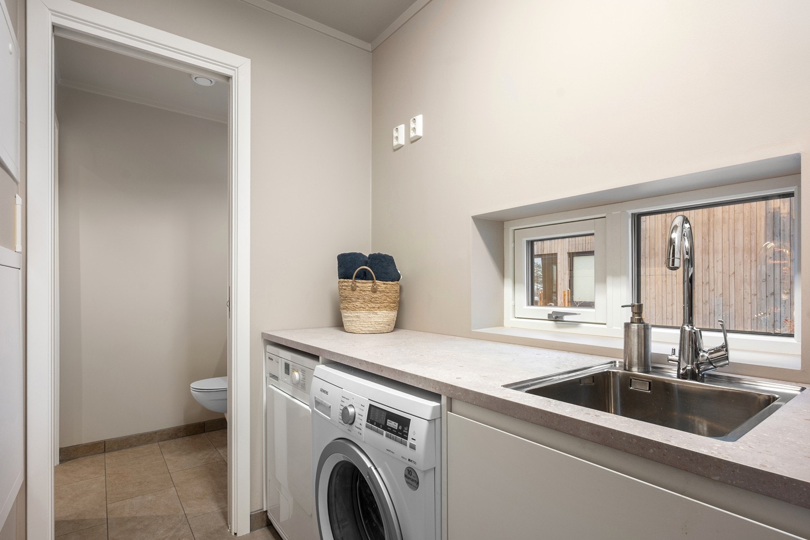 Fra toalettrommet er det adkomst til vaskerommet, som fremstår i tilsvarende utførelse. Vaskerommet har benkeplate med nedfelt utslagsvask, skap for oppbevaring samt opplegg for vaskemaskin og tørketrommel. Galleribilde