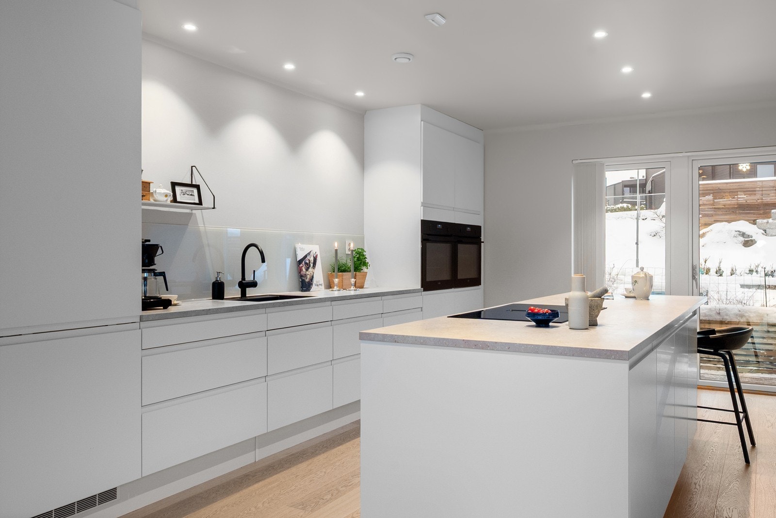 Hvitevarer er fra kvalitetsmerket AEG og består av platetopp med integrert ventilator, to stekeovner, oppvaskmaskin samt to kjøle- og fryseskap. Store vindusflater og utgang til uteplass gjør kjøkkenet til et naturlig samlingspunkt i boligen. Galleribilde