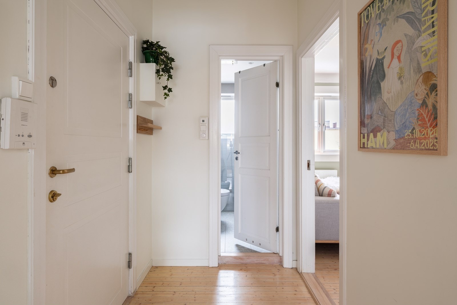 Innbydende entré med lysmalte vegger, originale tregulv og plass til oppheng av yttertøy. Galleribilde