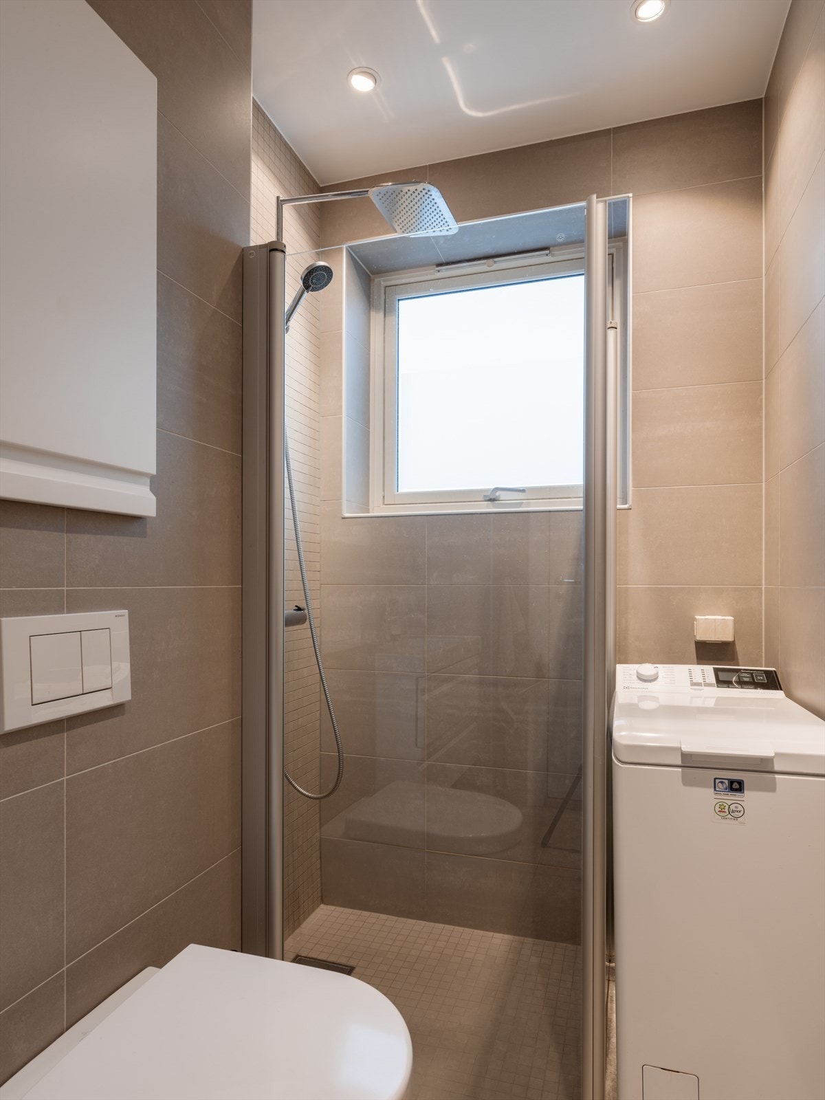 Innredningen består av servantskap med skuffer, speil, dusjhjørne med glassdører og vegghengt toalett. Galleribilde