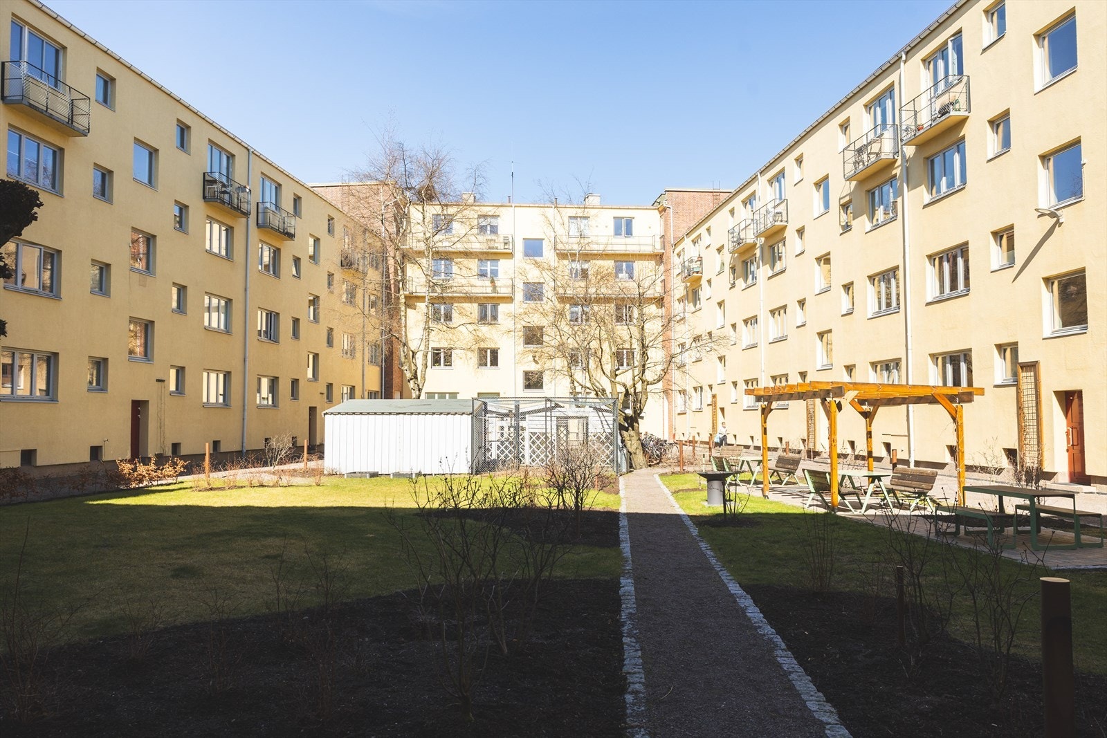 Lukket bakgård som er pent opparbeidet med sittegrupper, lekeplass og flotte trær Galleribilde