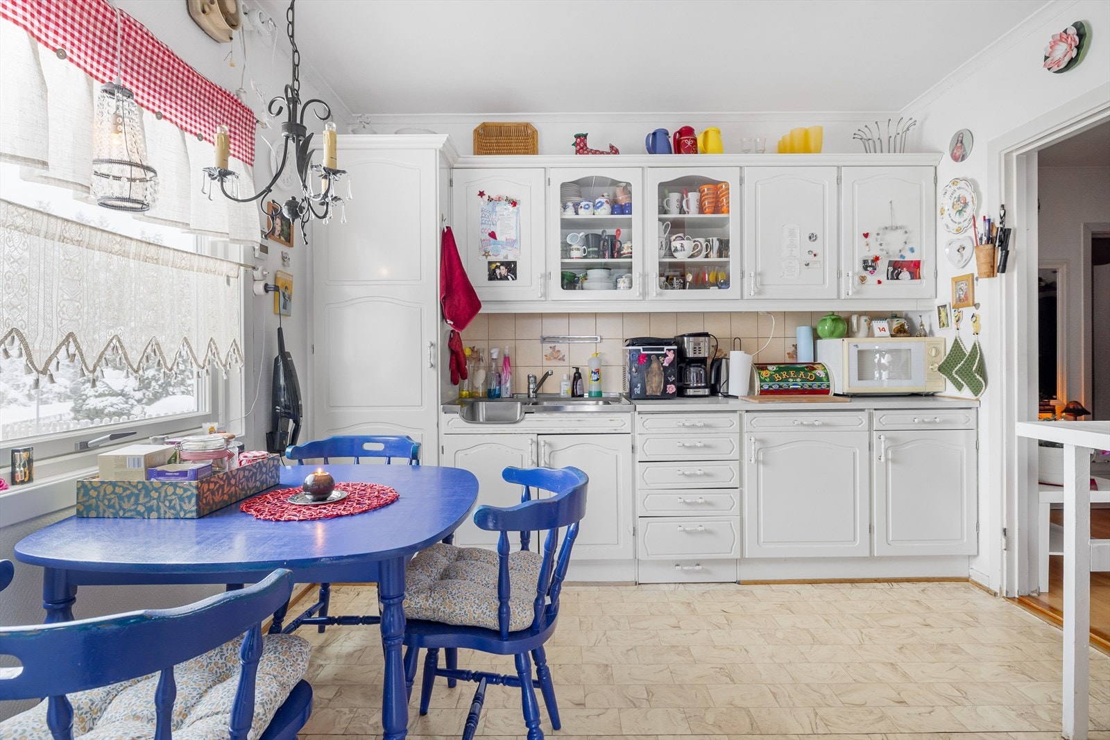 Lys kjøkkeninnredning med hvite profilerte fronter, laminert benkeplate, benkebeslag med nedfelt oppvaskkum og fliser i benkeryggen. Galleribilde