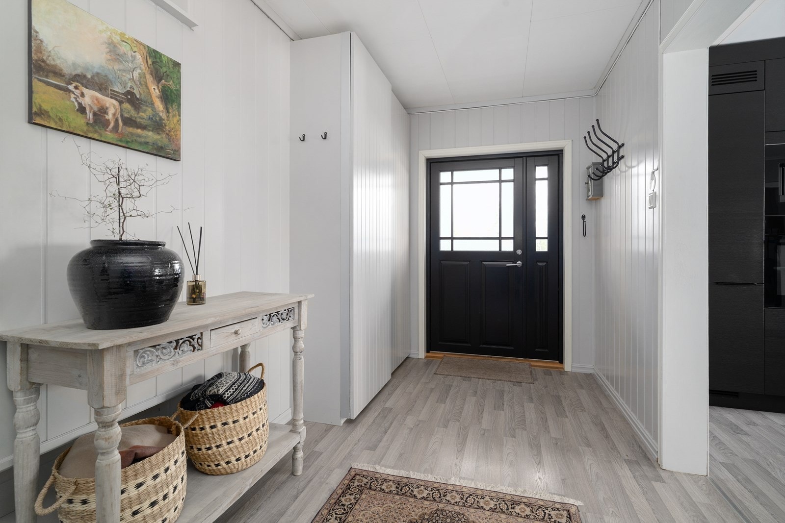 Via den staselige inngangsdøra kommer man inn i boligens gangareal med lysmalte overflater og plass til mindre møblering. Galleribilde