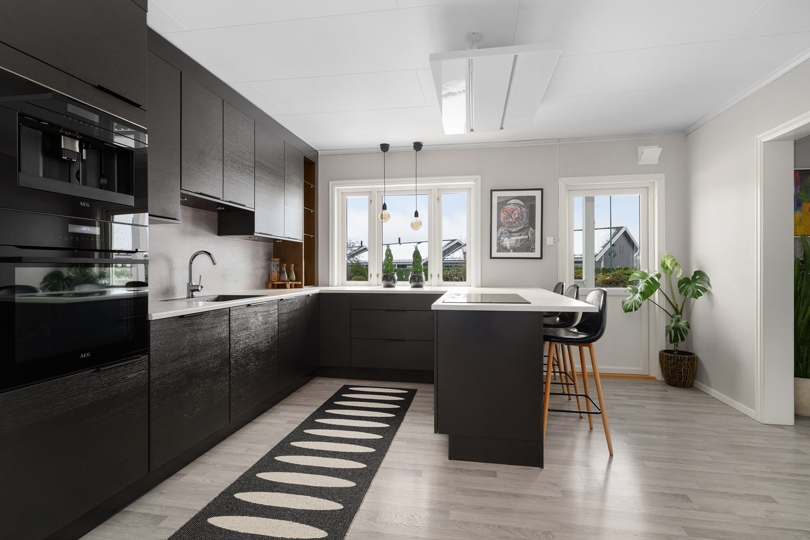 Kjøkkenet har integrerte hvitevarer som bred platetopp, oppvaskmaskin og kjøl/fryseskap, samt stekeovn og kaffemaskin plassert i praktisk arbeidshøyde i høyskapet. Galleribilde