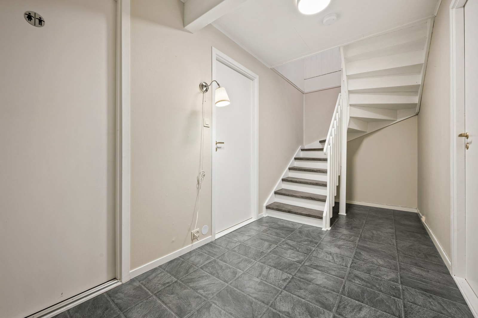 Videre leder gangen til to soverom, bad og vaskerom i første etasje, samt trapp til andre etasje. Galleribilde