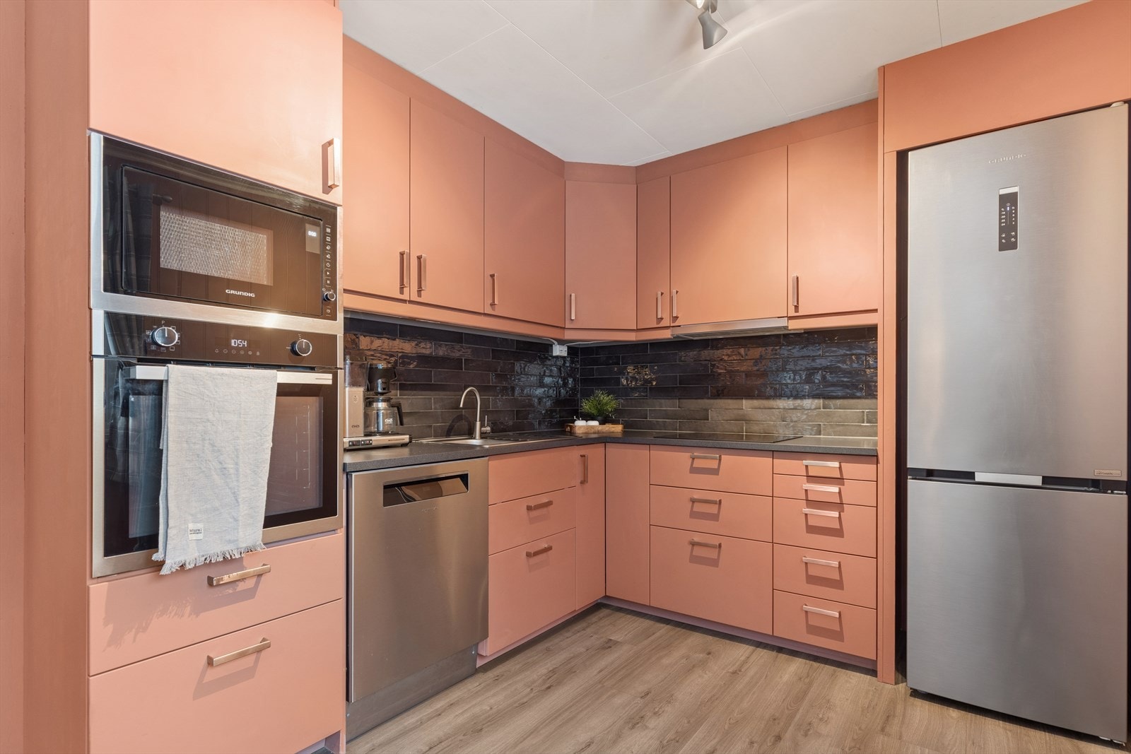 Vinkelinnredning med god skap- og skuffeplass. Stekeovn og mikrobølgeovn i ståhøyde. Galleribilde