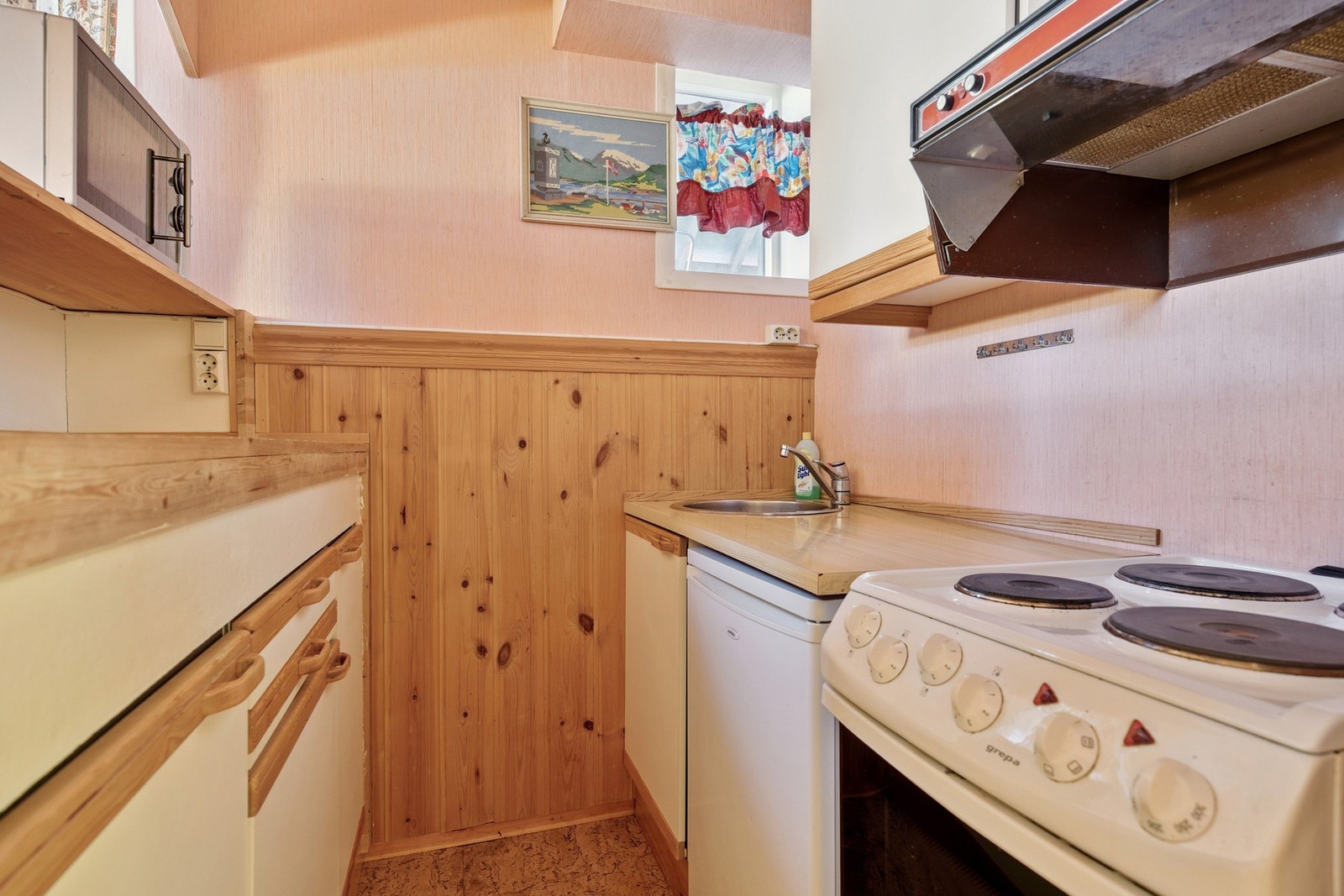 Kjøkkenet i kjeller er også en åpen løsning og fungerer godt som en selvstendig enhet. Innredningen er fra starten av 1990-tallet (ifølge eier), med glatte fronter, benkeplate i laminat og tre, nedfelt oppvaskkum og ventilator i overskap. Galleribilde