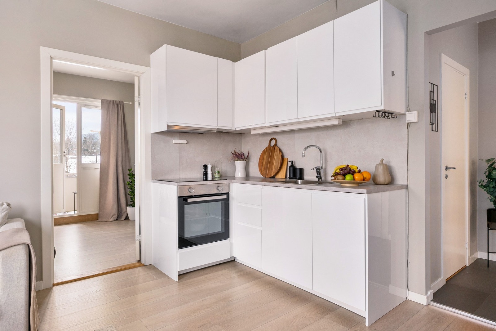 Pent og praktisk kjøkken med innredning bestående av hvite, glatte fronter. Galleribilde