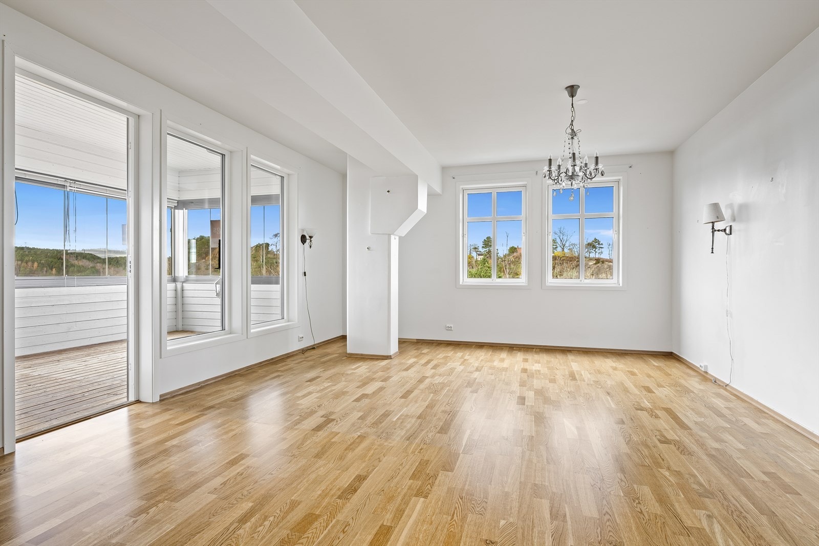 Stue med store vindusflater og adkomst videre ut på innglasset balkong Galleribilde