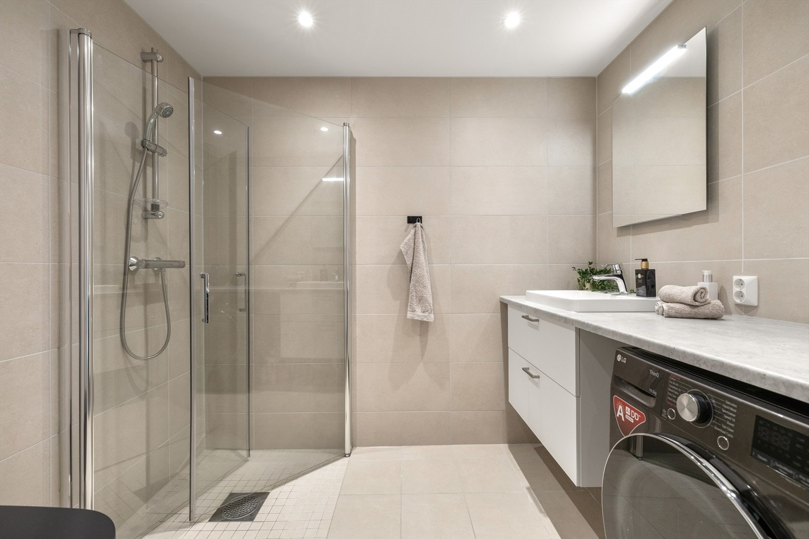 Delikat, flislagt bad med romslig dusjhjørne og moderne innredning. Galleribilde