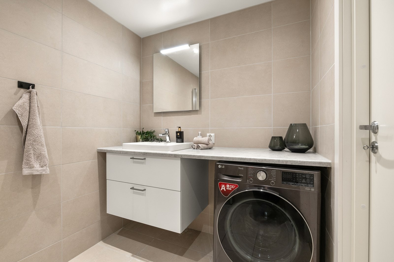 Praktisk og stilrent bad med opplegg for vaskemaskin og god benkeplass. Galleribilde