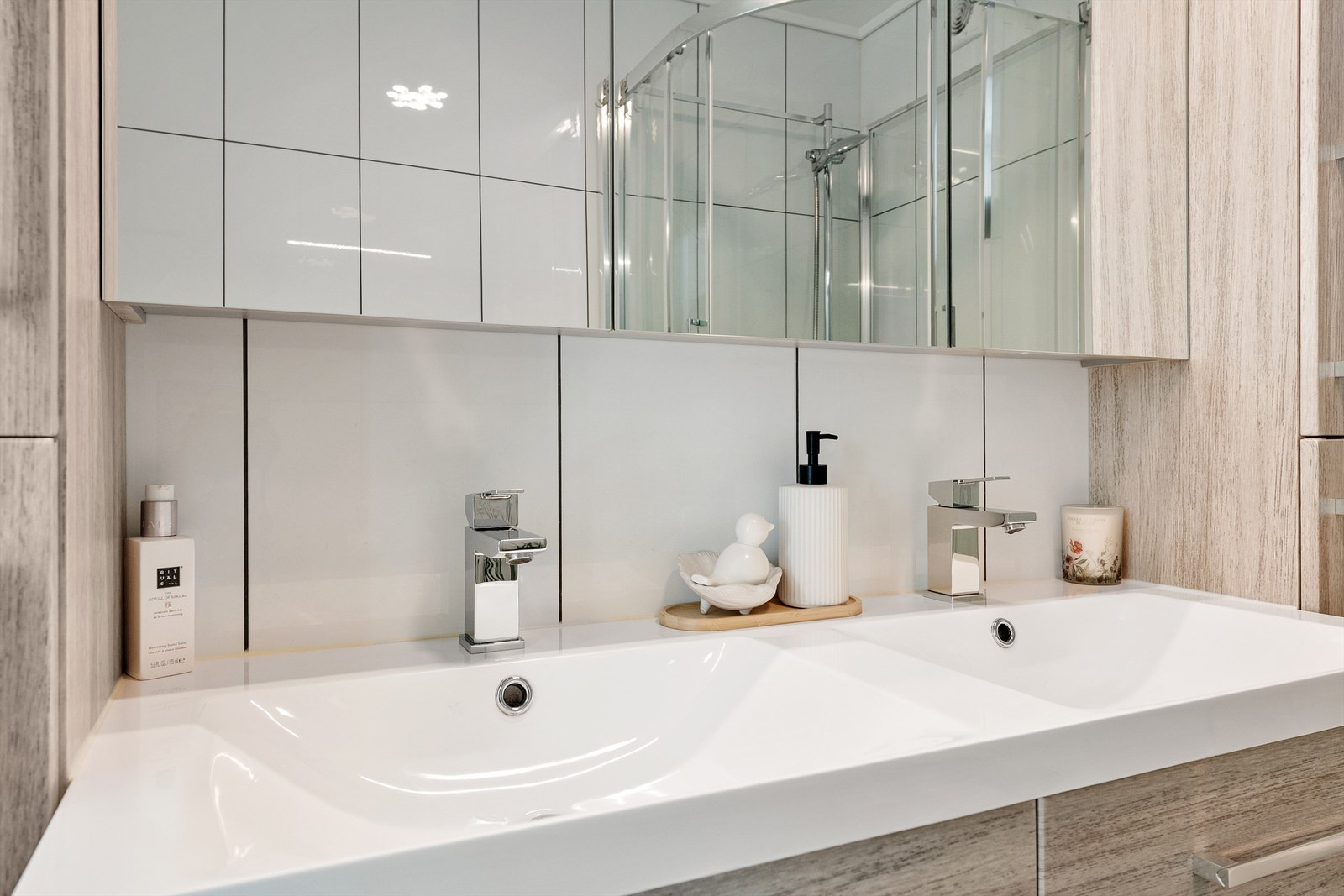 Detaljefoto fra bad med dobbel servant med ett-greps armaturer. Speilskap over servant Galleribilde