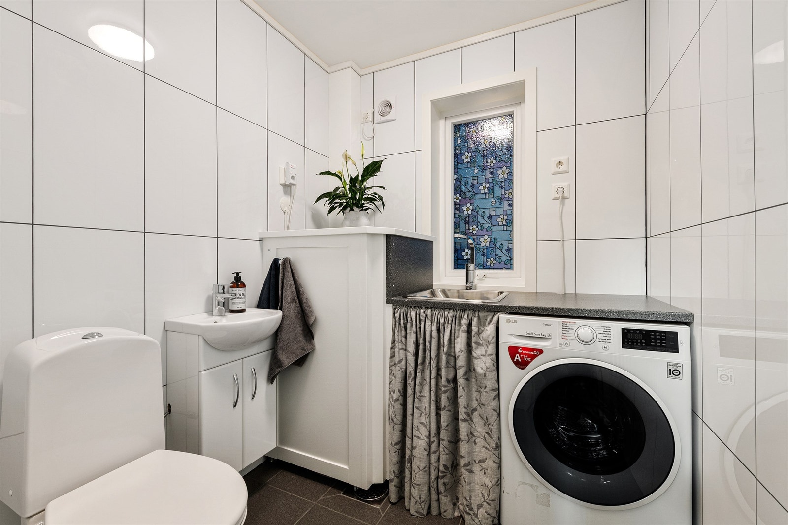 Vaskerom i underetasjen med toalett, servantinnredning og opplegg for vaskemaskin Galleribilde