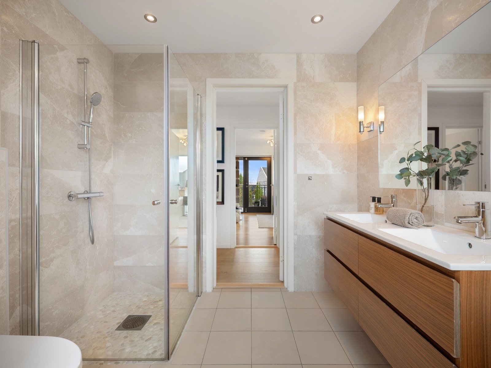 Innredet med dobbel servant med glattfinerte fronter, helstøpte servantbenker og speil med belysning. Dusjhjørne med glassdører og vegghengt toalett. Galleribilde