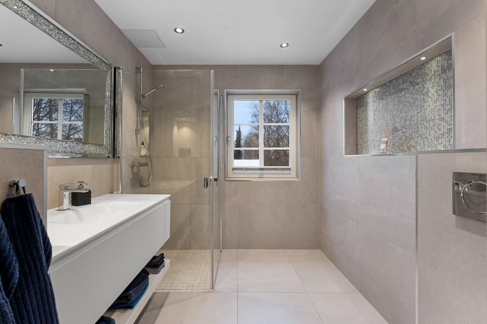 Lekkert baderom fra 2020 med fliser på gulv med gulvvarme, fliser på vegger og nedsenket himling med downlights Galleribilde