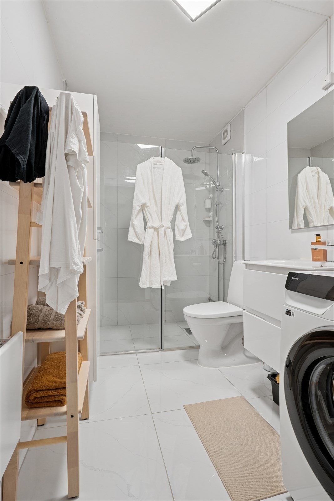 Badet er flislagt og utstyrt med vegghengt toalett og dusjhjørne. Galleribilde