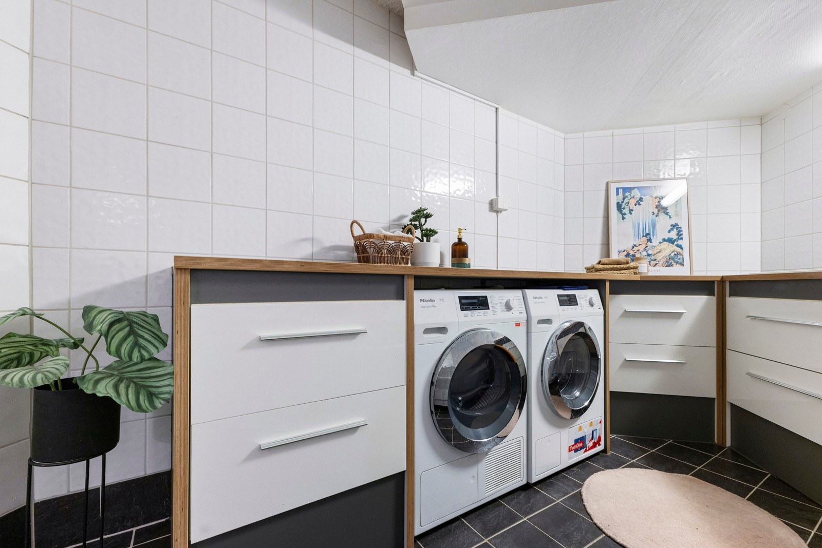 Rommet er tilrettelagt med opplegg for vaskemaskin, og har i dag en løsning med flere vaskemaskiner integrert under benk, noe som gir en ryddig og effektiv vaskesone med god arbeidsflate over. Galleribilde