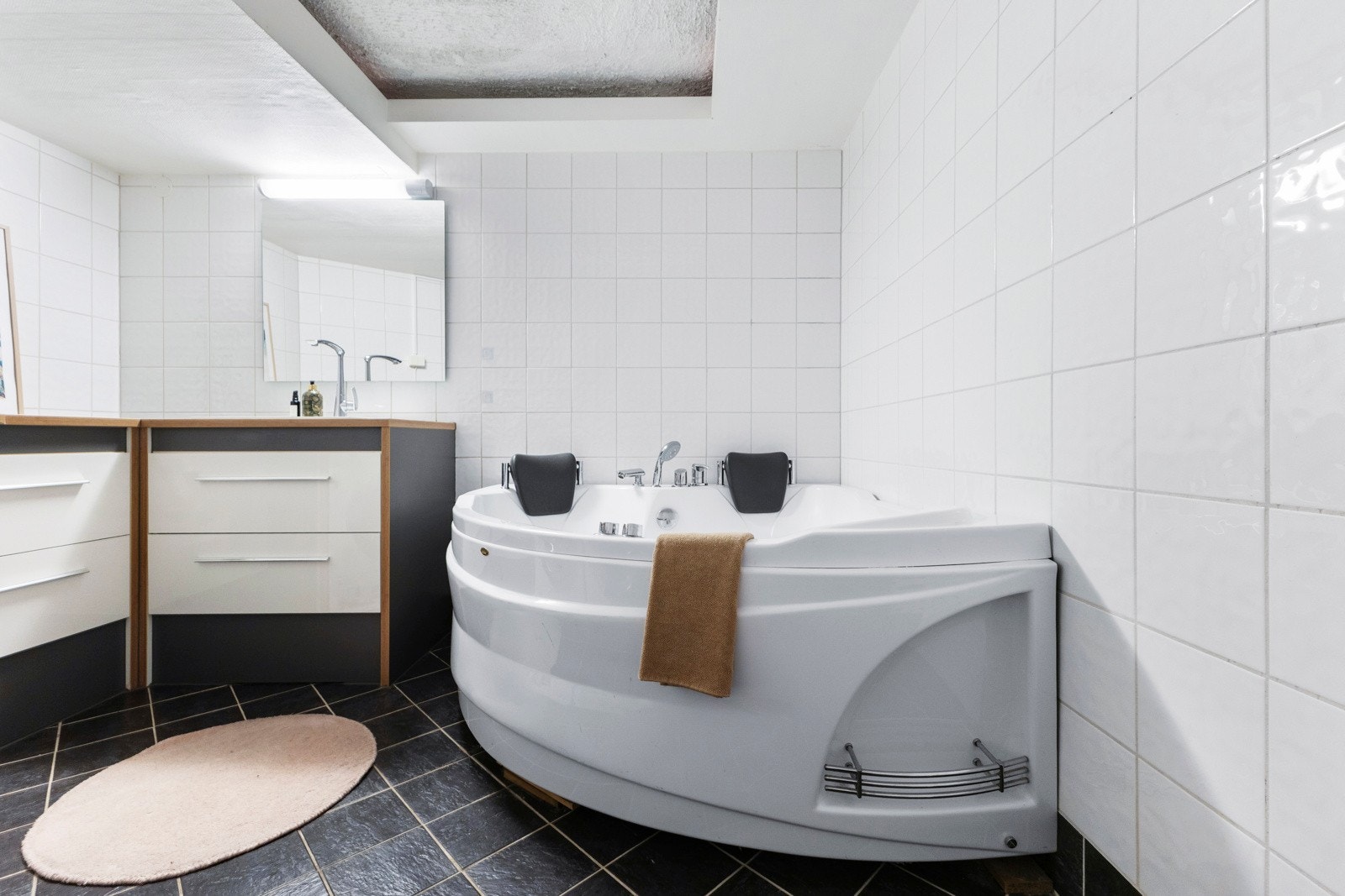 Badet er innredet med glatt baderomsinnredning med servant nedfelt i underskap, speil med belysning, samt boblebadekar med dusjløsning. Galleribilde