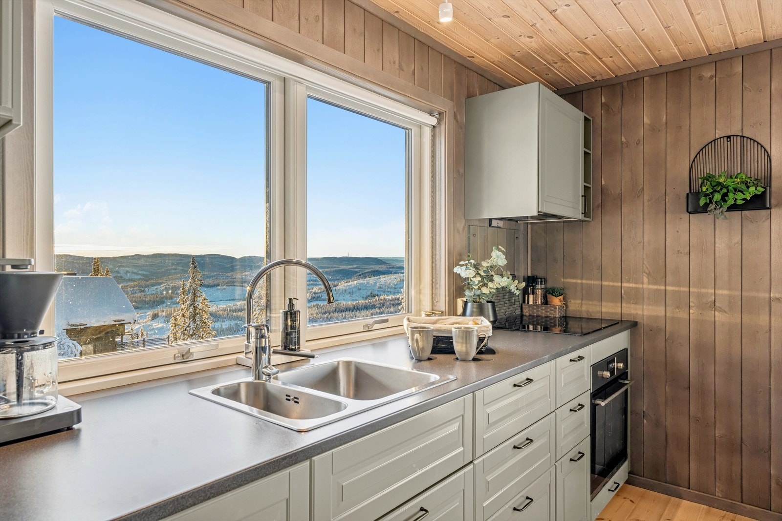 Kjøkkenet er innredet med en pen og tidløs løsning fra IKEA, med grå profilerte fronter og laminert benkeplate med integrert kjøkkenkum. Galleribilde