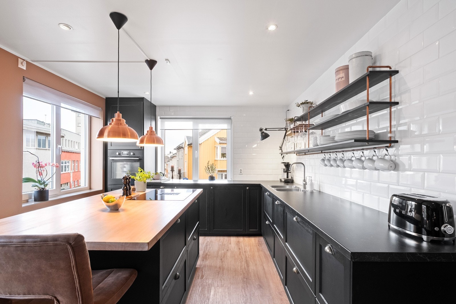 Stilrent og moderne kjøkken fra 2020, med kjøkkenøy, integrerte hvitevarer og avtrekksvifte bygget inn i koketoppen. Galleribilde