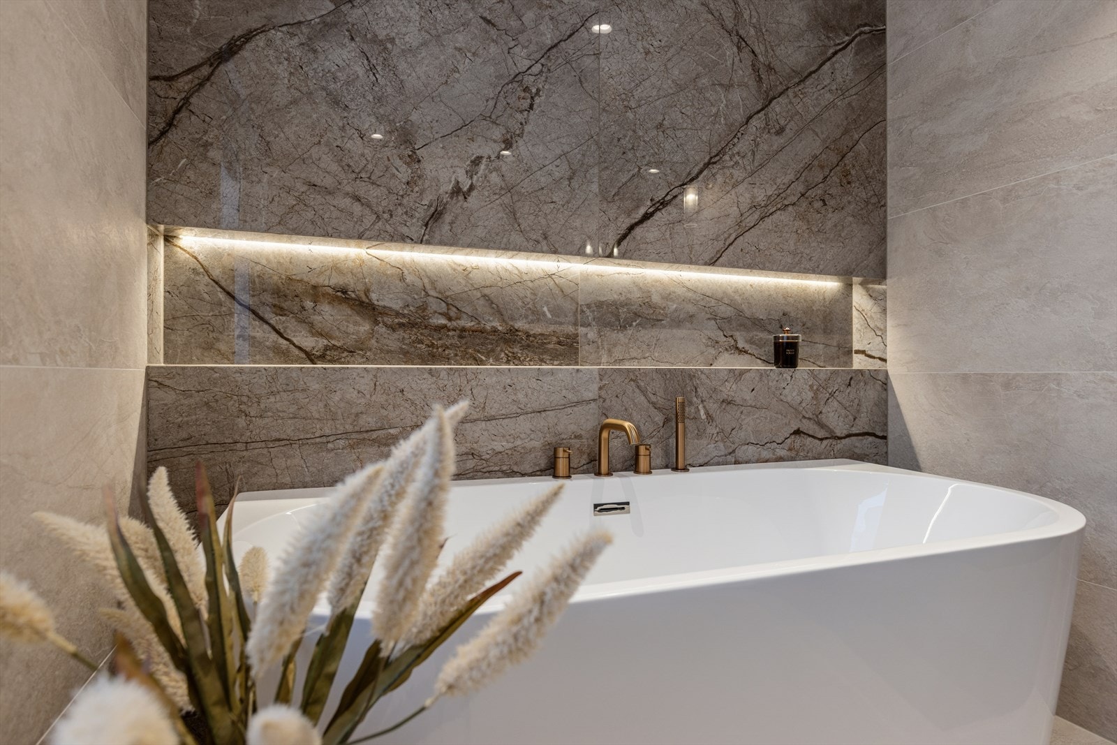 En delikat, innfelt hylle med belysning gir praktisk oppbevaring ved badekaret. Galleribilde