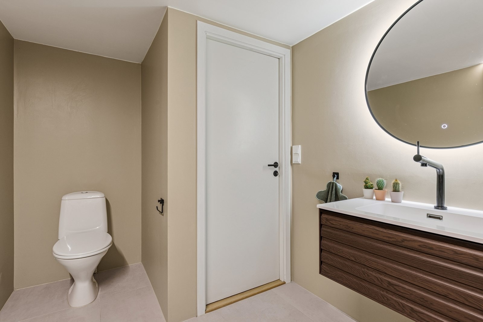 Detaljer som det bakbelyste speilet og mørke armaturer gir badet et helhetlig preg. Galleribilde