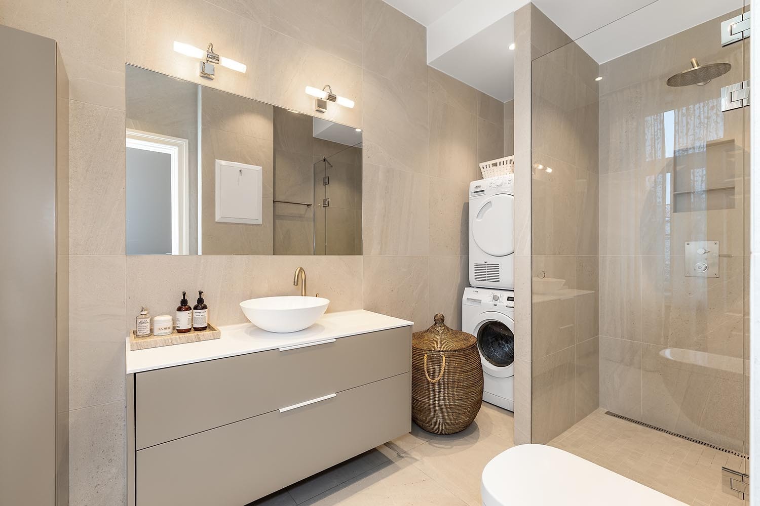 Pent flislagt bad med toalett, ser vant, dusj og opplegg for vaskemaskin. Galleribilde