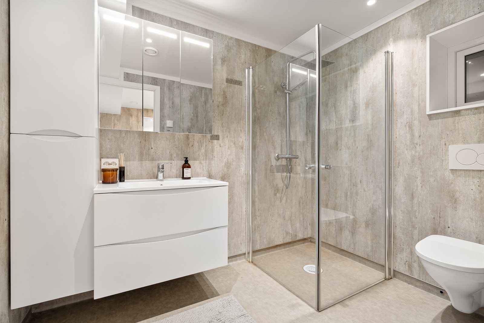 Bad med vegghengt toalett, servant med innredning og dusjhjørne Galleribilde