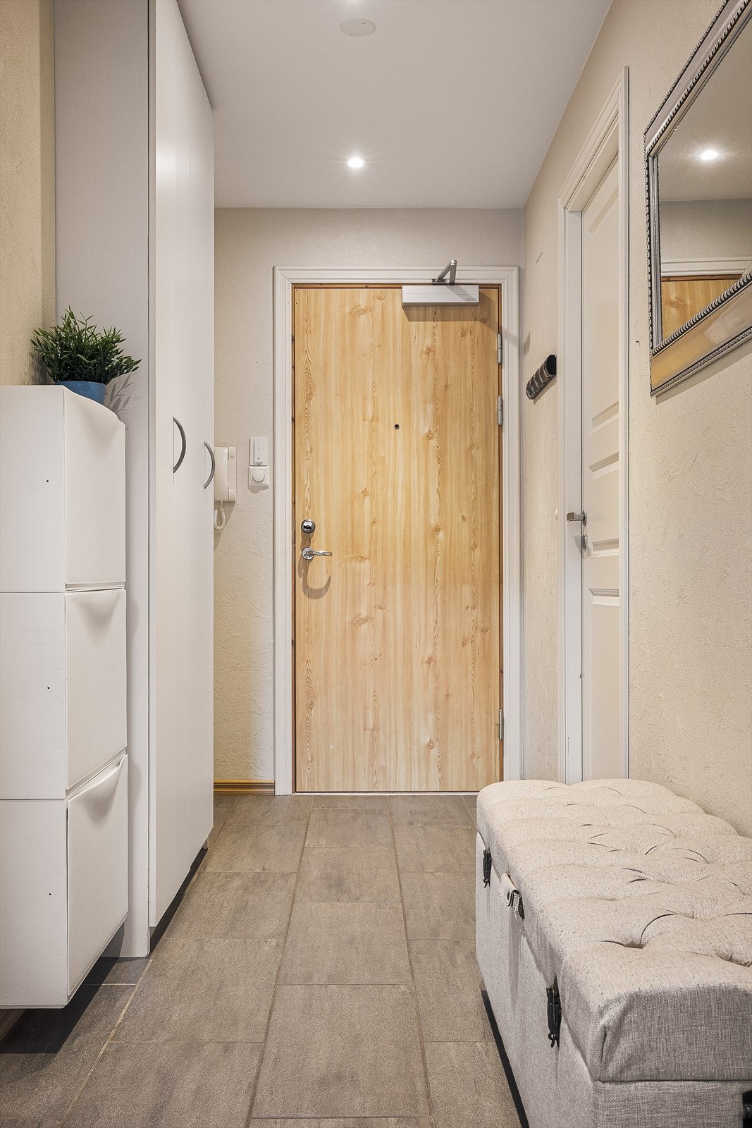 Gang har fliser på gulv, lysmalte vegger og tak og med innfelte spotlights i tak Galleribilde