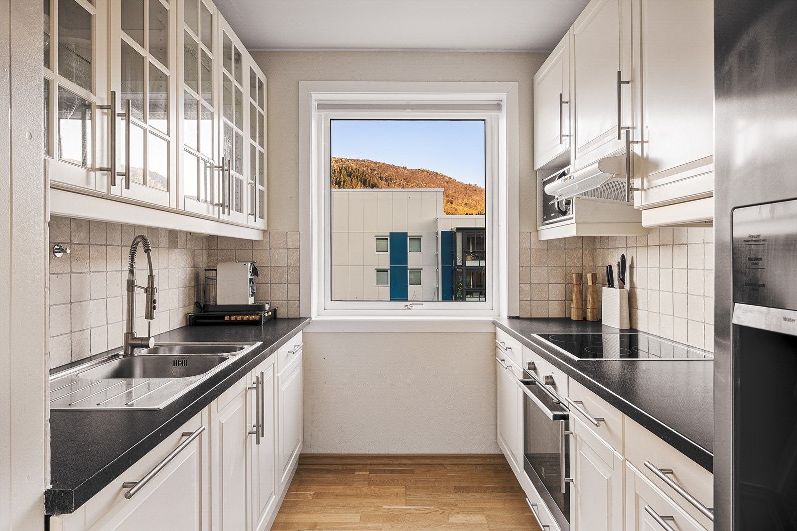 Tidløst kjøkken med hvite profilerte fronter og noen overskap med glassfronter Galleribilde