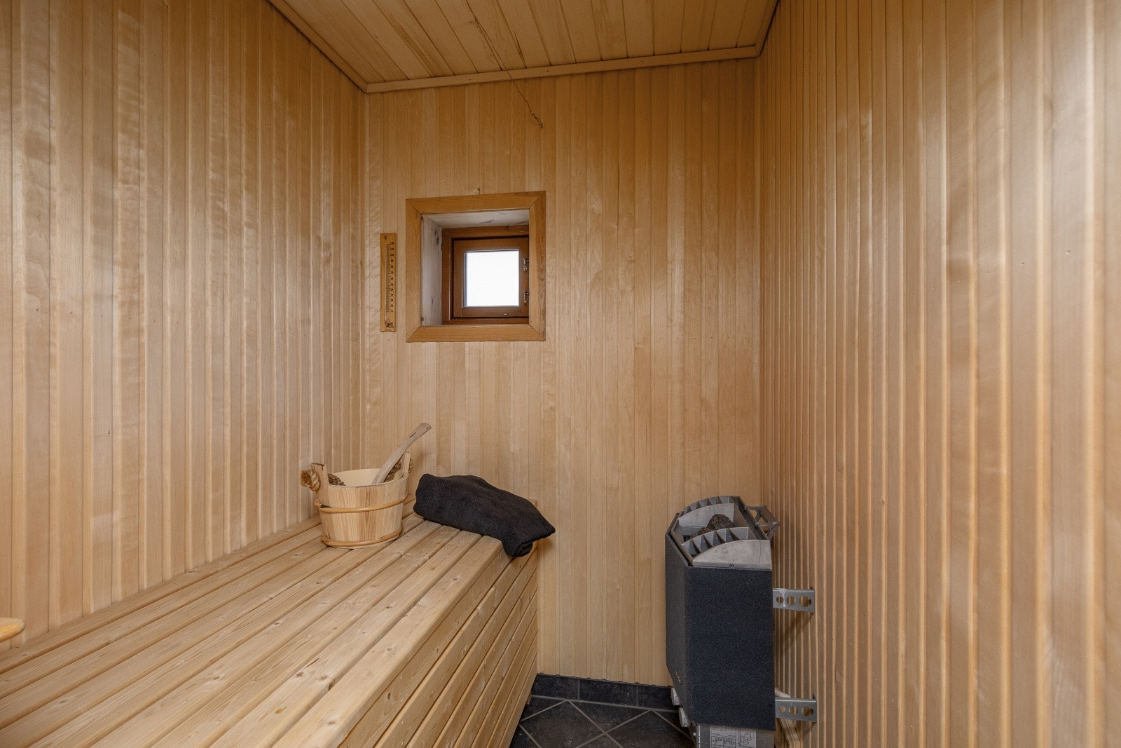 Badstuen har fliser på gulv, panel på vegg og i tak. Galleribilde