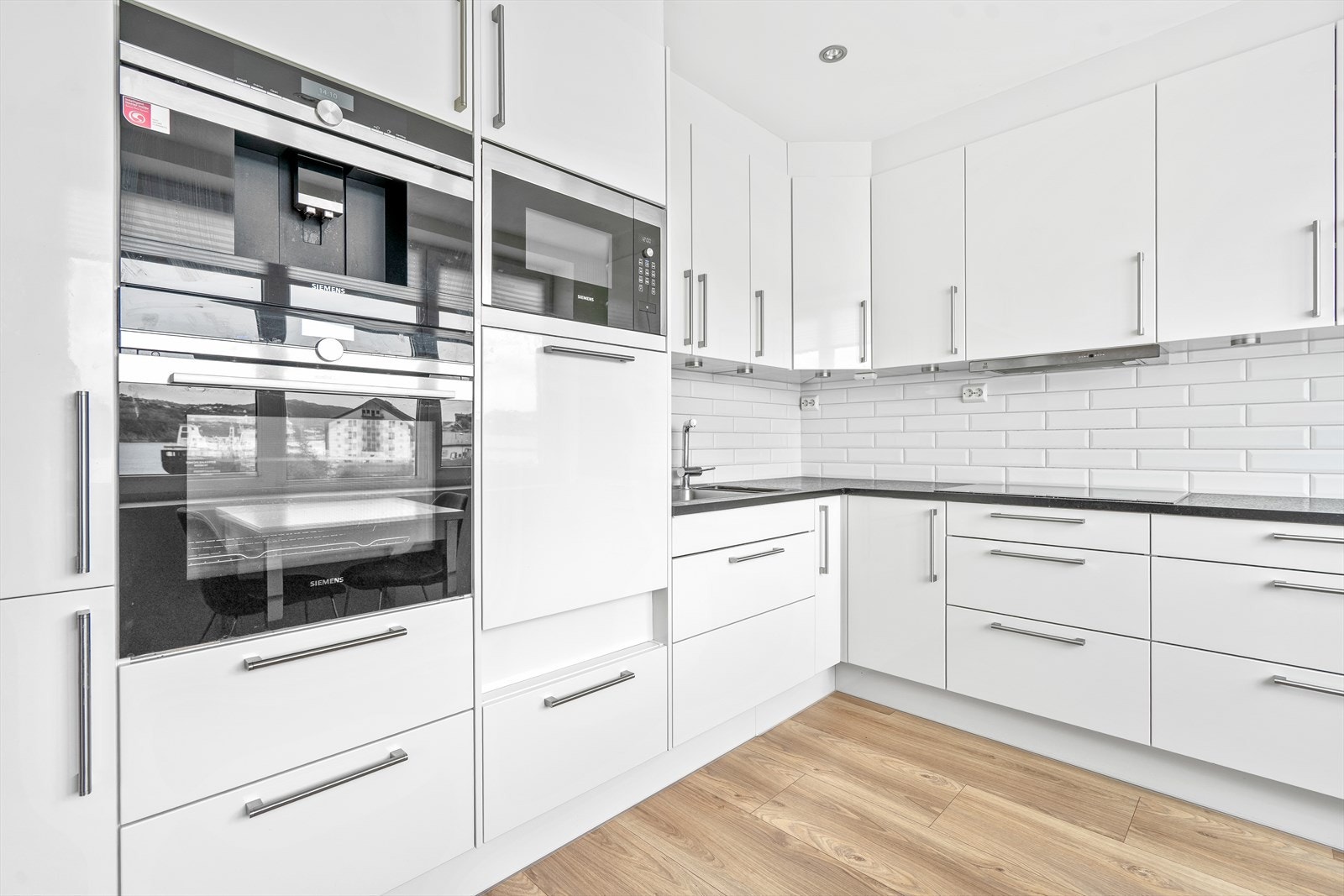Lys og moderne kjøkken med integrerte Siemens hvitevarer og rikelig skapplass Galleribilde