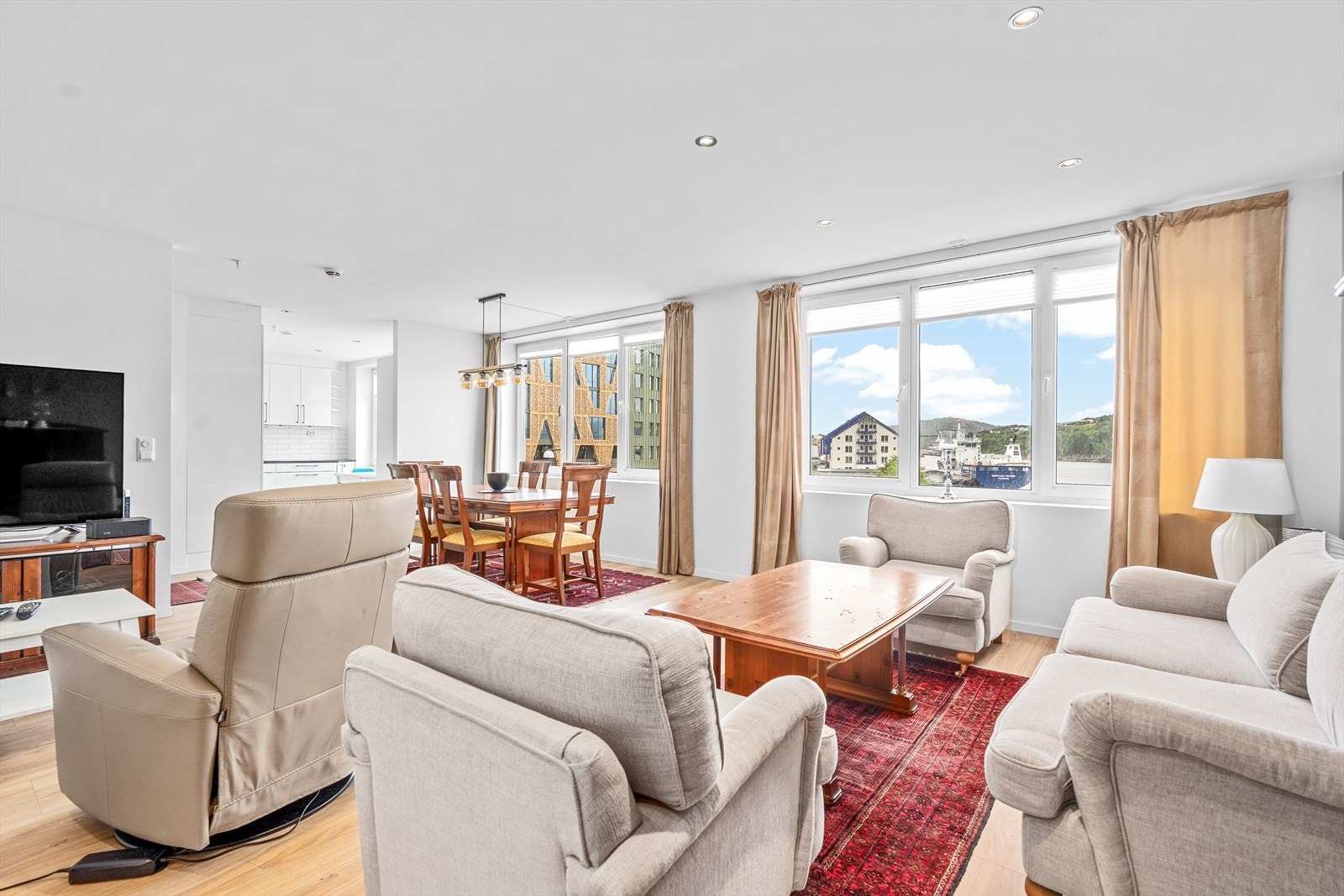 Stor og lys stue med store vindusflater, god plass til både sofagruppe og spisebord Galleribilde