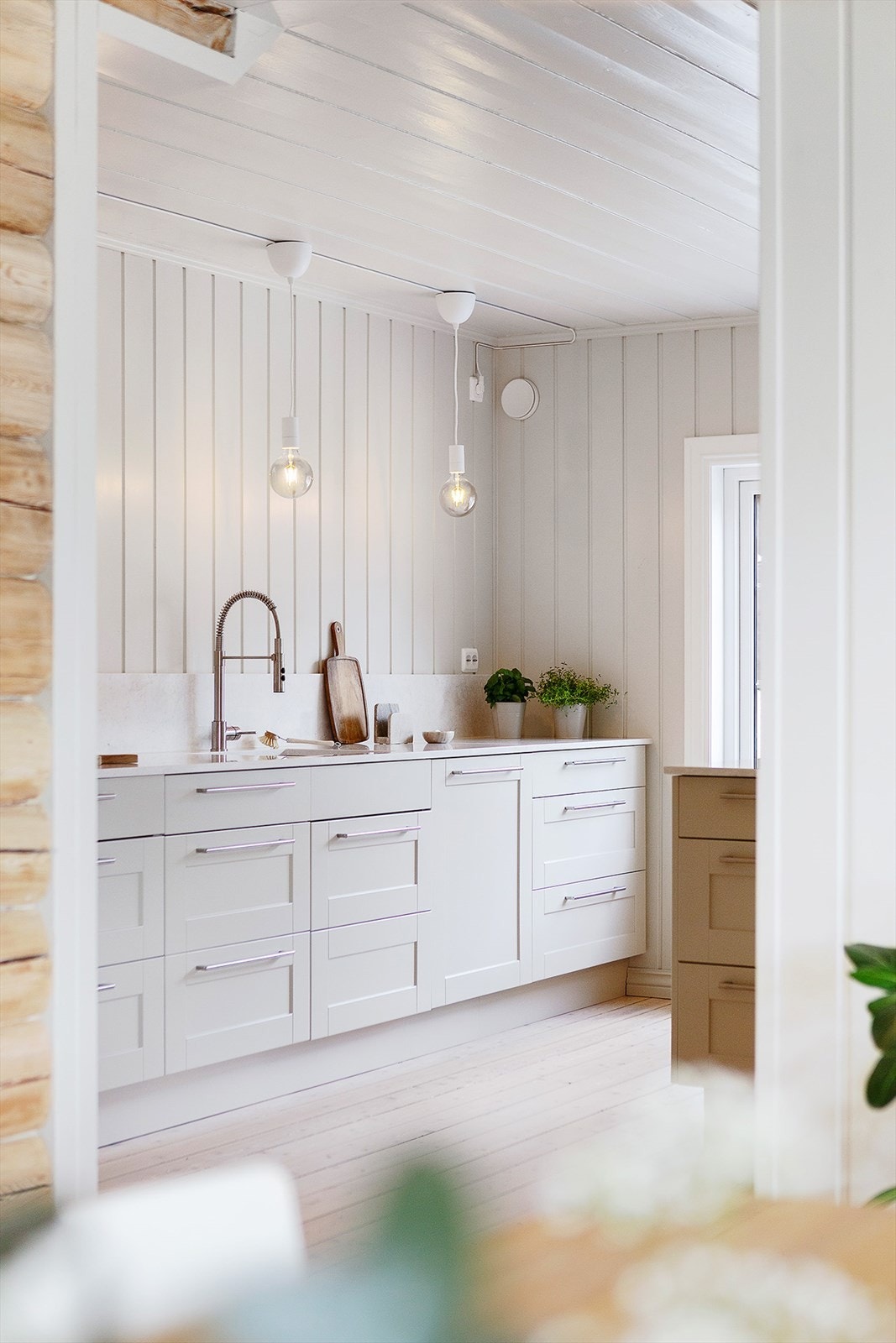 Delikat Huseby-kjøkkeninnredning med lyse profilerte fronter og benkeplater i stein (2025) med nedfelt oppvaskkum i rustfritt stål og ett-greps vannkran. Galleribilde