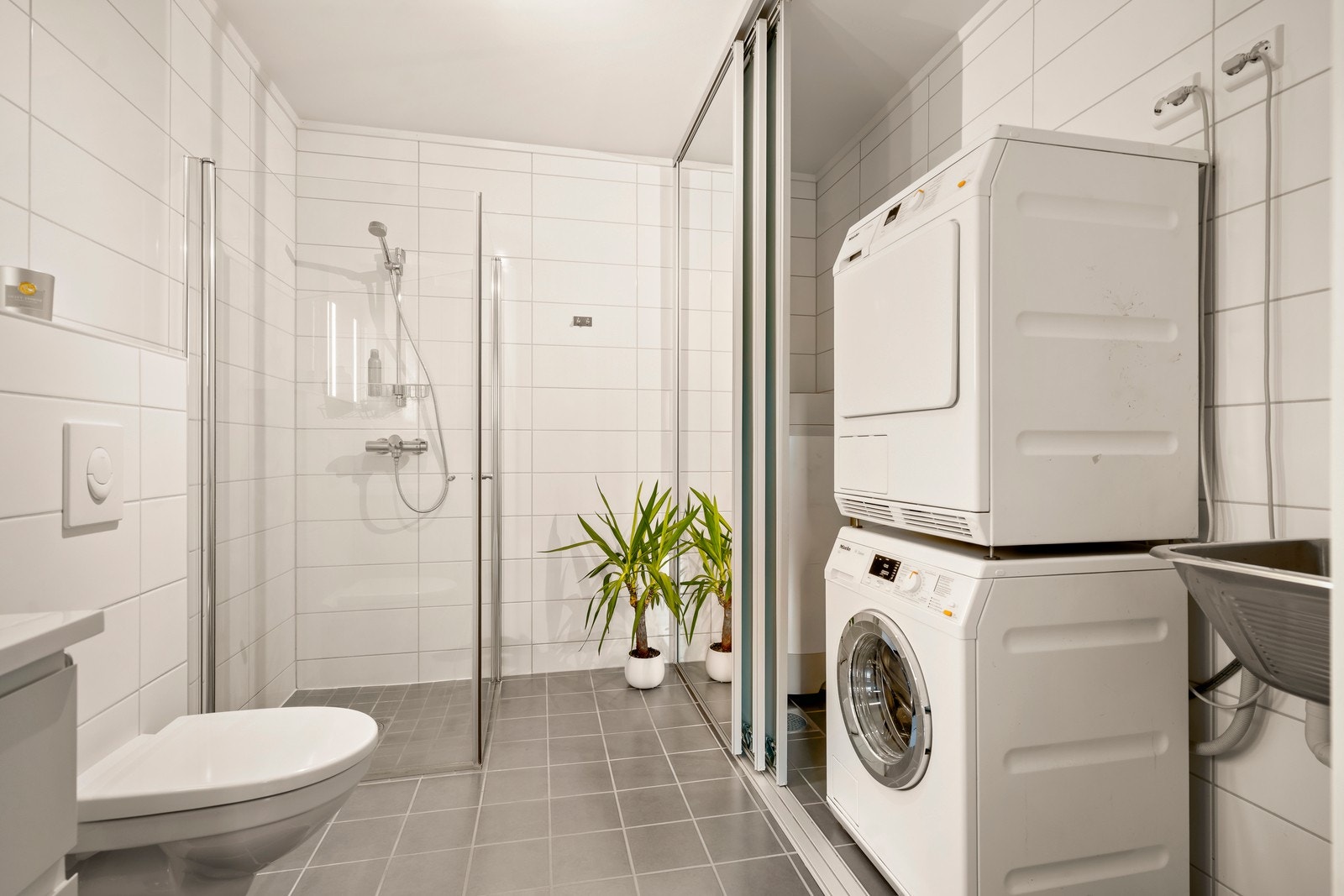 Rommet er utstyrt med en innredning med nedfelt servant, veggmontert toalett, dusjhjørne, skyllekum og opplegg for vaskemaskin. Galleribilde