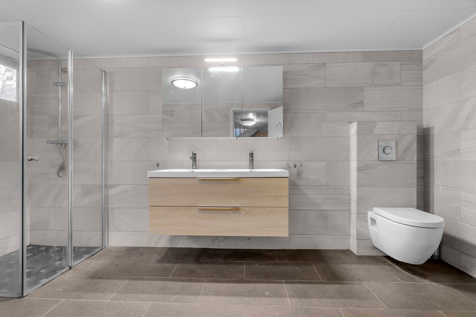 Badet er utstyrt med en praktisk innredning med dobbelvask, vegghengt WC, boblebad og dusjgarnityr. Galleribilde