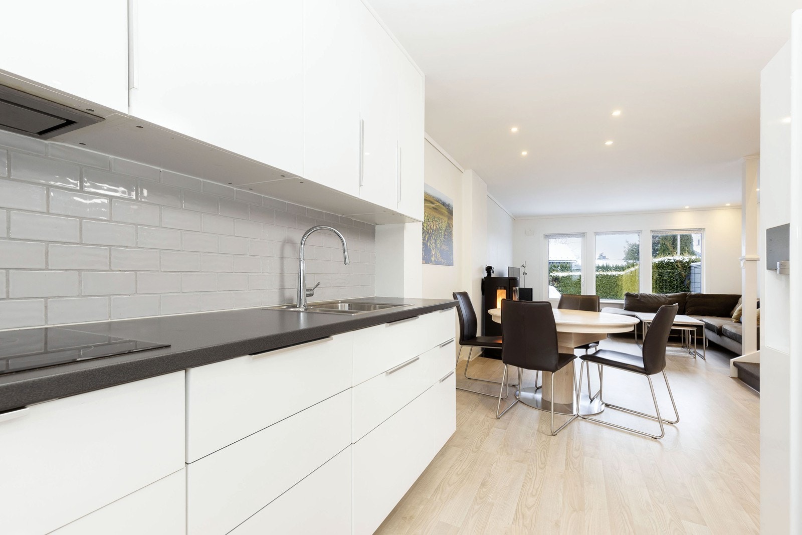 Kjøkkeninnredning i hvit høyglans med praktiske fliser over kjøkkenbenk Galleribilde