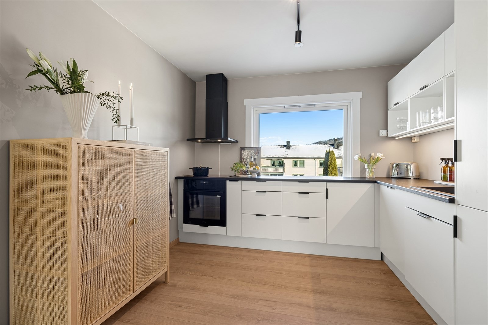 Stilrent kjøkken fra Systemkjøkken (2022). Kjøkkeninnredningen har hvite, slette fronter og laminert benkeplate. Komposittkum med ett grep blandebatteri. Malte flater på vegg under overskap. Det er montert komfyrvakt og lekkasjestopper. Galleribilde